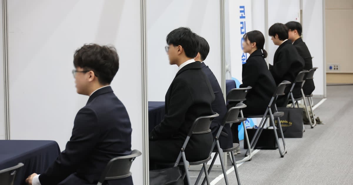 ** Job seekers interviewing at employment fair booths in Busan, South Korea convention center