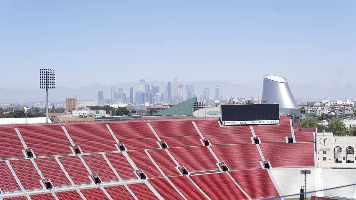 White arched entrance of historic Los Angeles Memorial Coliseum under sunny blue sky