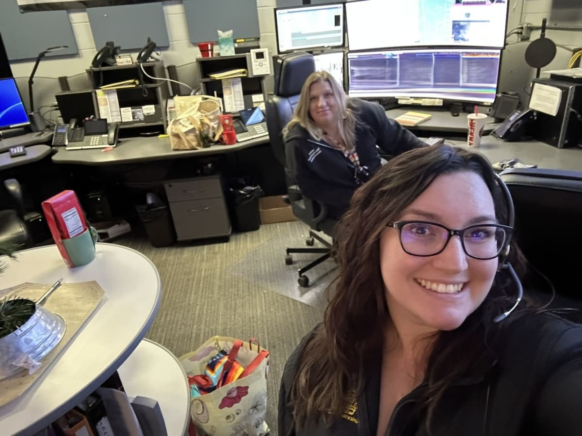 Young woman wearing dispatcher headset working at emergency call center desk