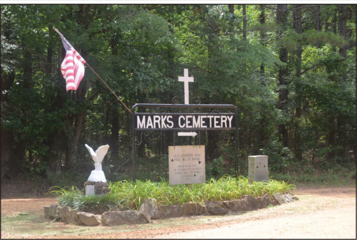 Historic cemetery entrance sign for Marks Family Reunion among pine trees in rural Arkansas