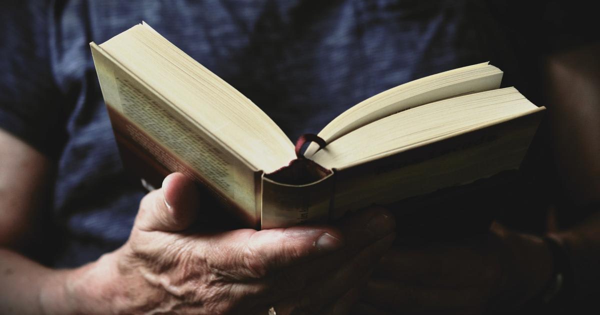 Open book on table with Welsh countryside visible through window in background