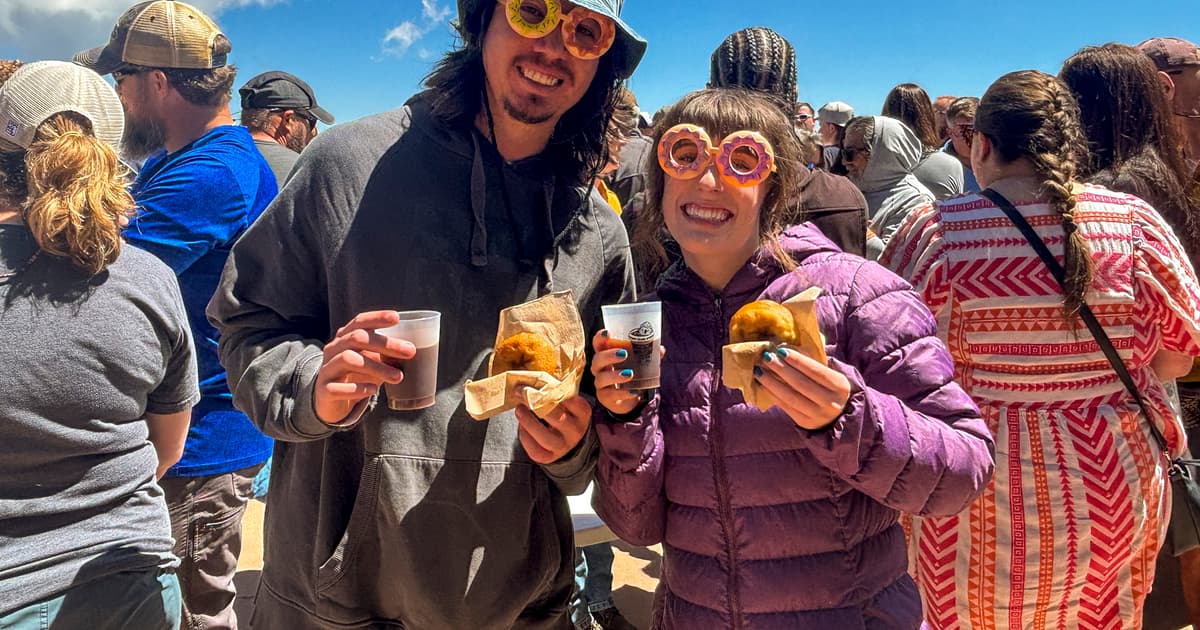 Large crowd gathered at Pikes Peak summit holding donuts and coffee cups for world record attempt