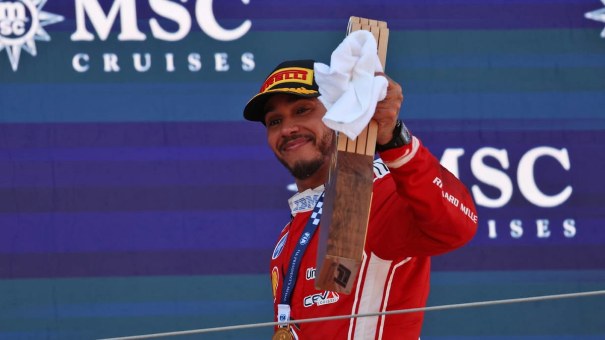 ** Lewis Hamilton celebrates on podium in red Ferrari racing suit after Barcelona Grand Prix victory