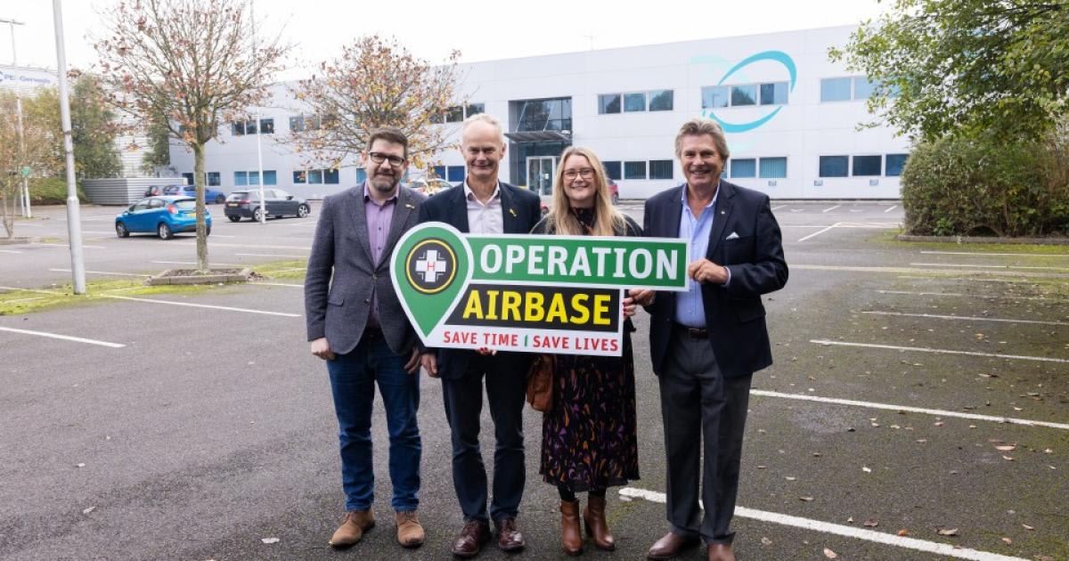 Four people standing outside modern air ambulance headquarters building near completion