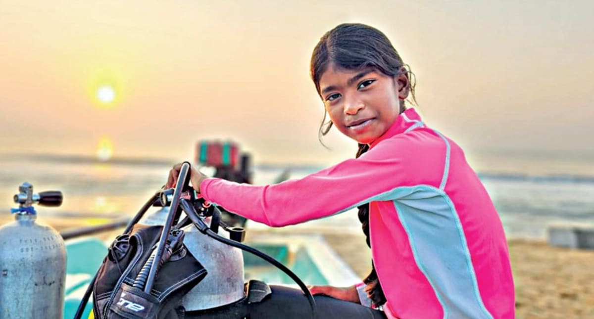 Young female diver underwater removing plastic debris from ocean floor near marine life