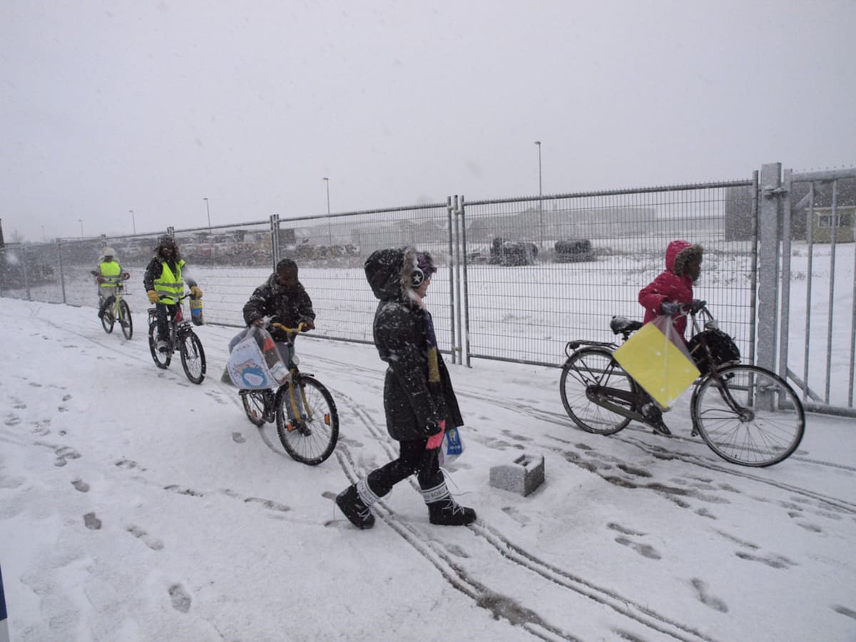 Families walk near temporary asylum shelter facilities in the Netherlands during reform investigation