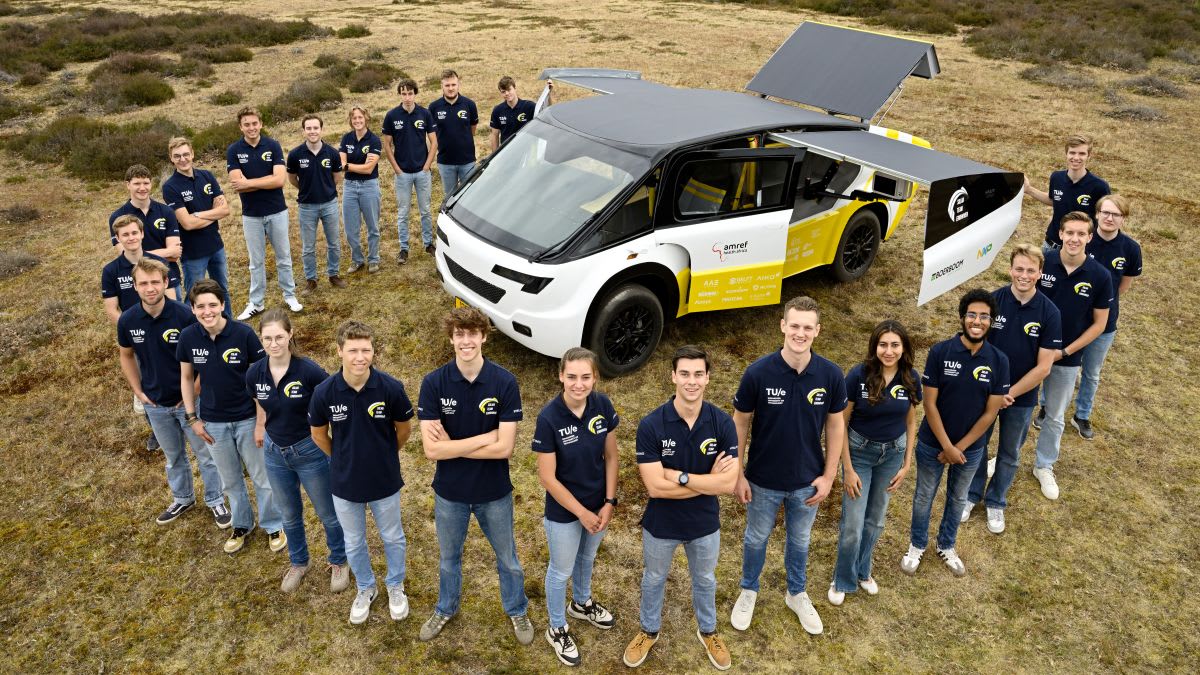 Solar Team Eindhoven standing beside white Stella Juva solar-powered ambulance with roof panels