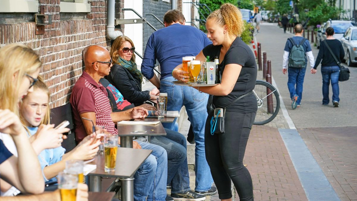 Dutch workers in modern office celebrating positive employment statistics with charts showing economic growth