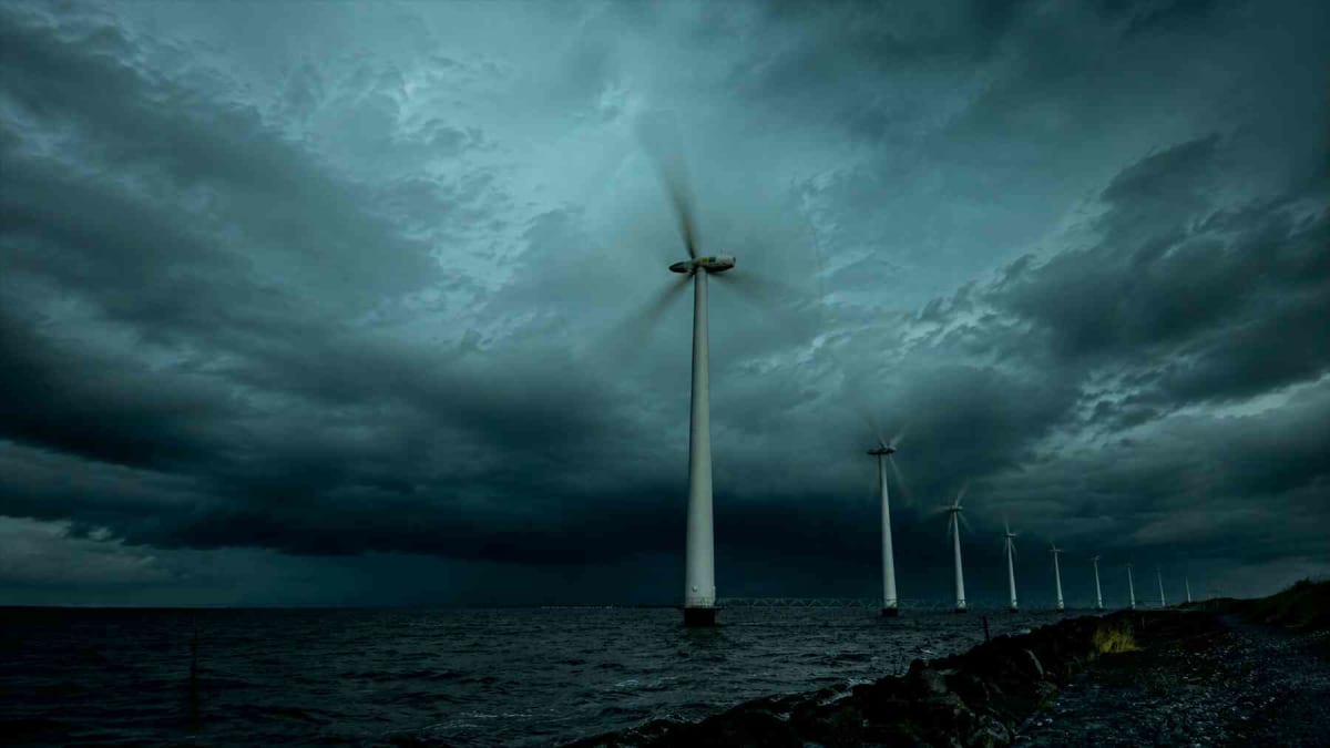 Offshore wind turbines spinning in ocean waters under clear sky creating atmospheric wake patterns