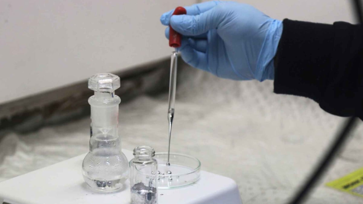 Scientists observing liquid gallium droplets in water under laboratory lighting conditions