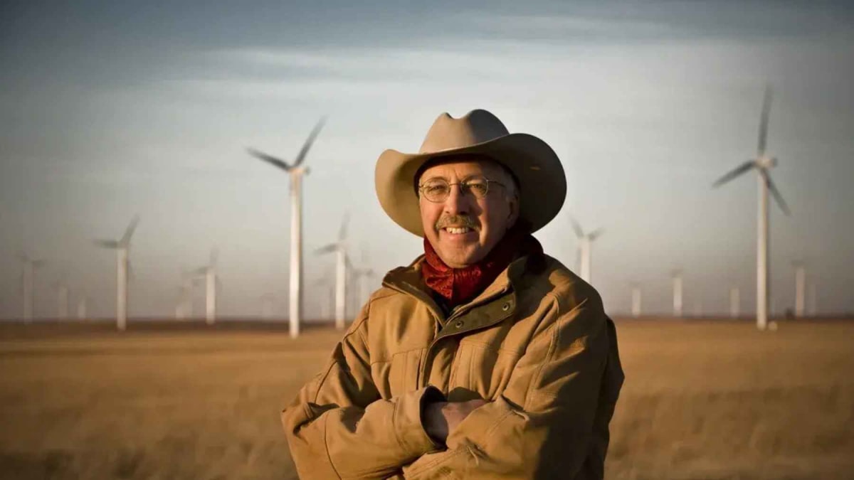 Cattle grazing peacefully beneath tall white wind turbines on Kansas prairie grassland