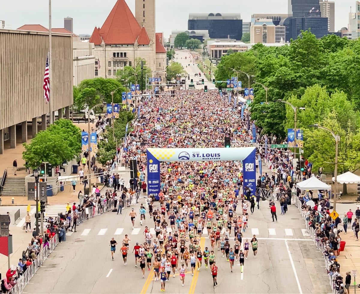 Runner in vintage powder blue Cardinals baseball uniform carrying bat and glove during race
