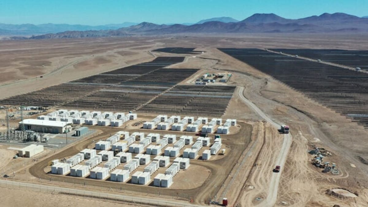 ** Large solar panel array stretching across Chile's Atacama Desert with mountains in background