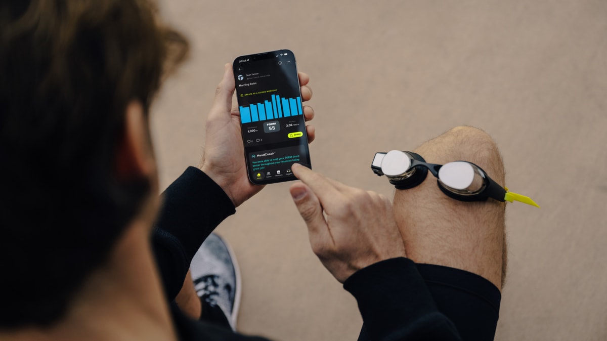 Swimmer wearing Form smart goggles with heads-up display showing training metrics in pool