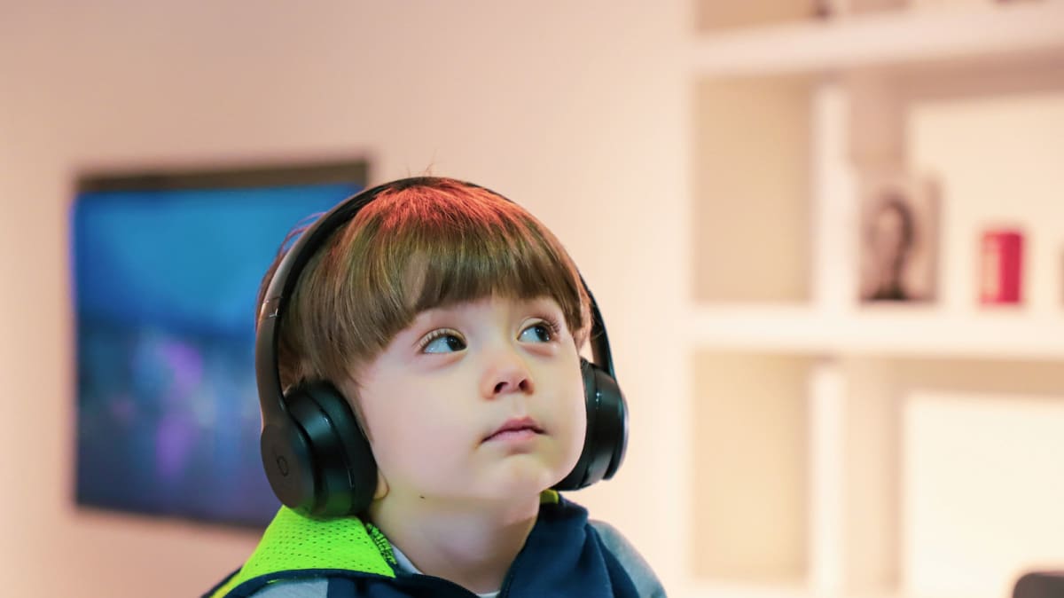Parent and child sharing headphones while looking at smartphone displaying Spotify music app interface