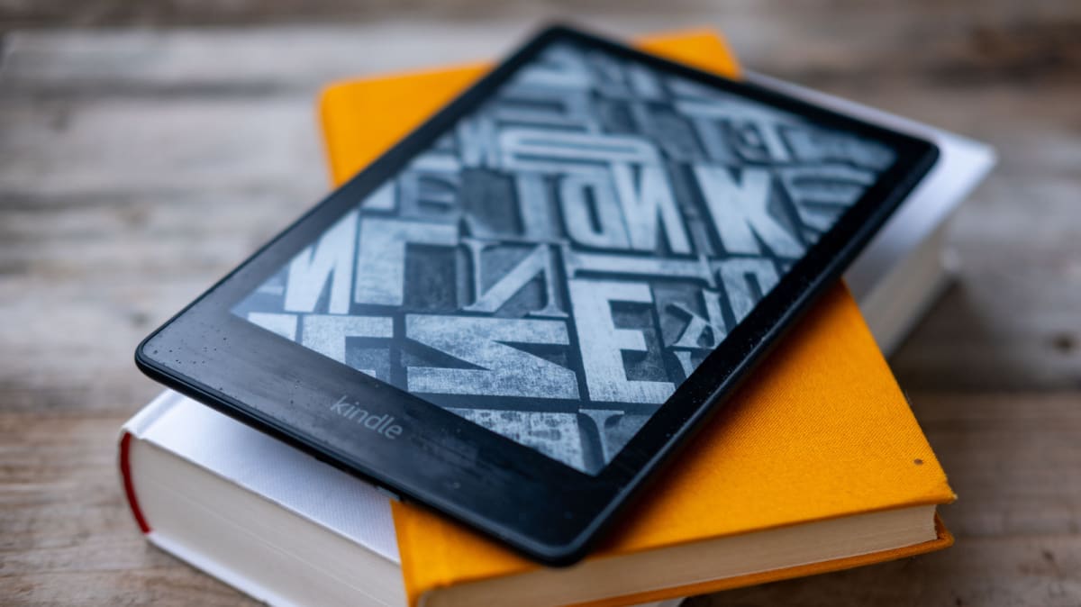 Person reading on Kindle e-reader device while relaxing comfortably at home