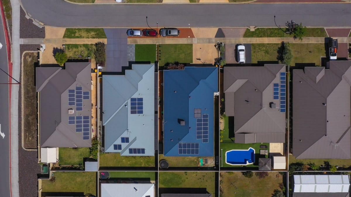Modern home battery storage unit mounted on wall next to solar panels on Australian rooftop