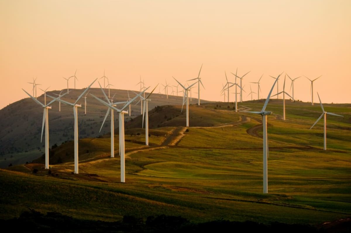 Wind turbines and hydroelectric dam in Swedish landscape under bright Nordic sky