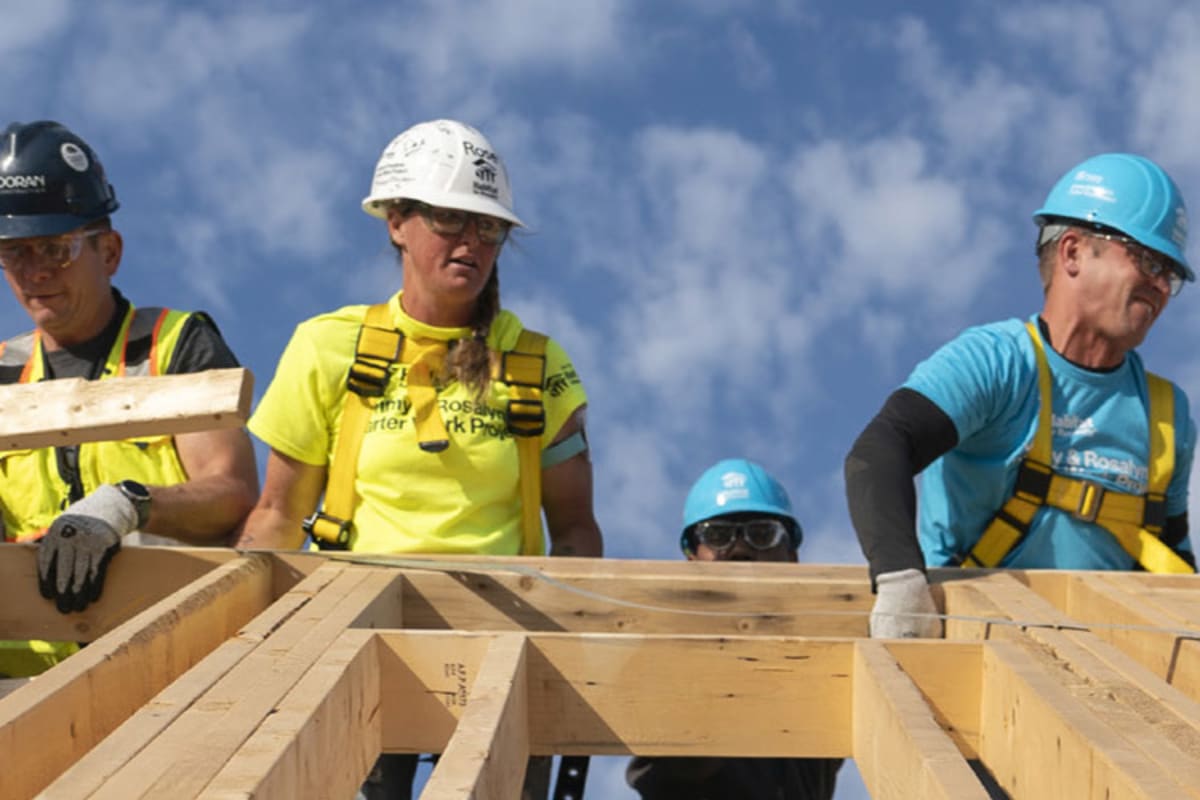 Volunteers in safety vests working together to frame walls for Habitat for Humanity home construction