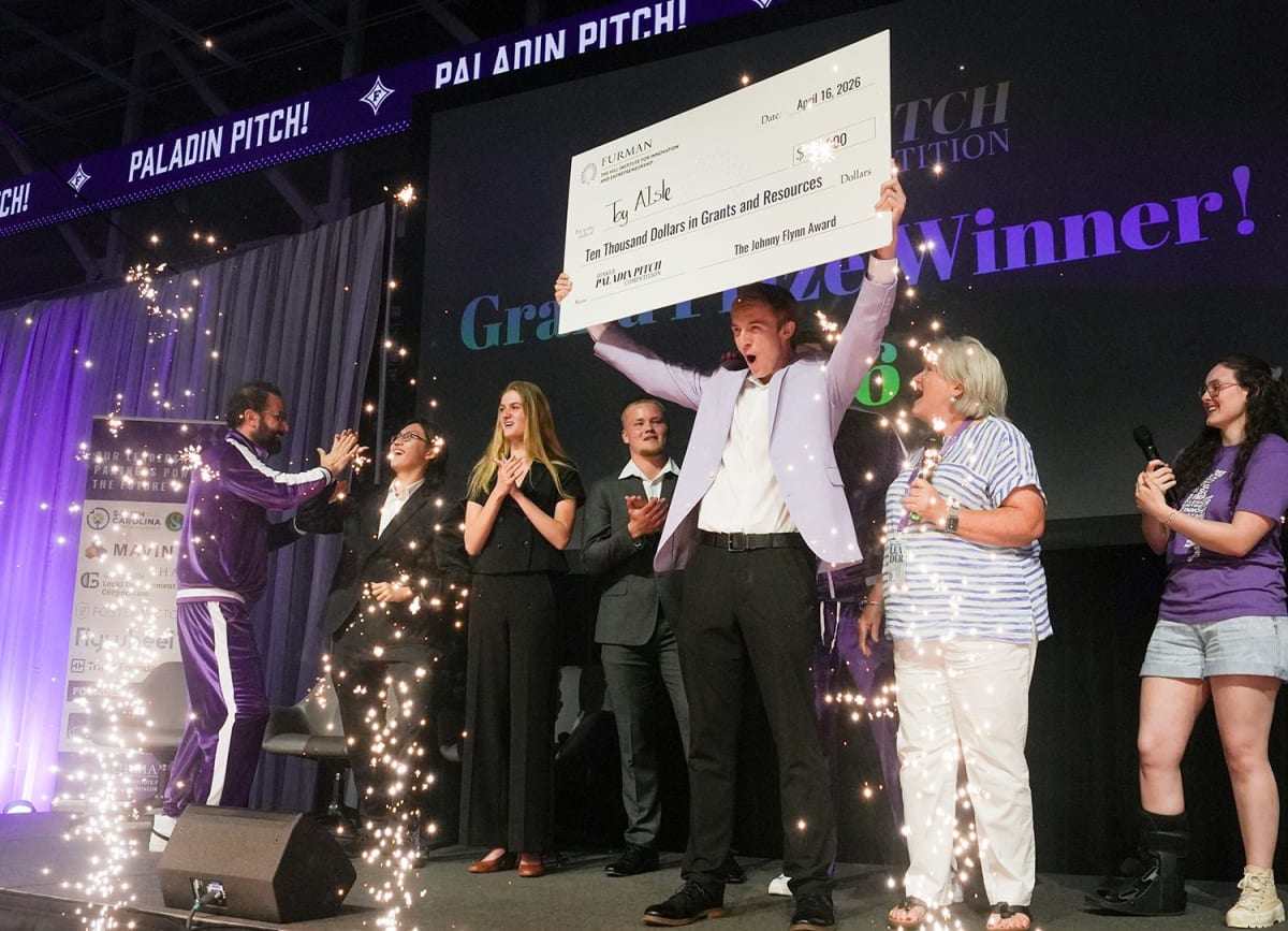 College student Camden Johnson celebrates winning pitch competition on basketball court stage