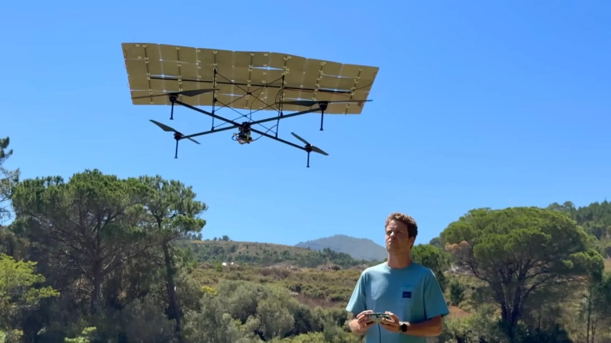 Custom-built solar-powered quadcopter drone with stacked panels hovering in clear blue sky