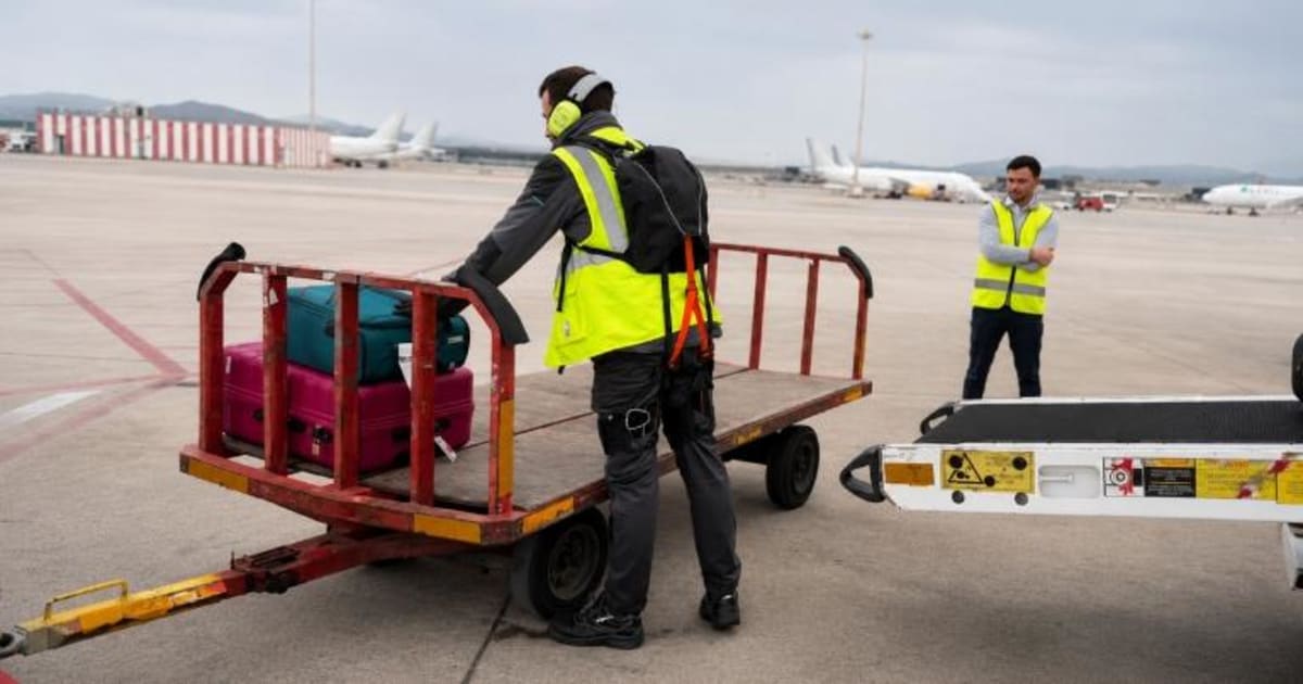 Baggage handler wearing lightweight robotic exosuit while lifting luggage at airport