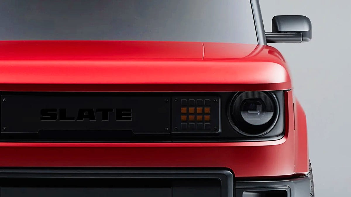 Workers preparing custom vinyl wrap kits for electric pickup trucks at manufacturing facility