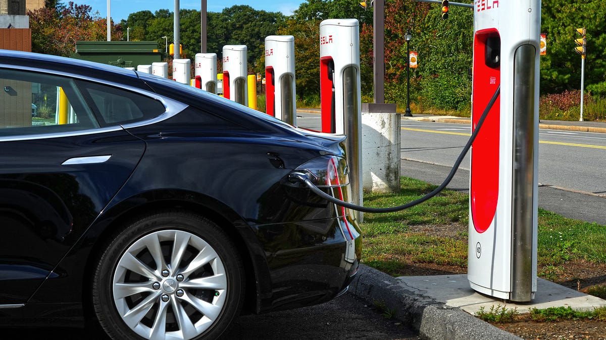 Electric vehicle plugged into public charging station with multiple charging ports visible