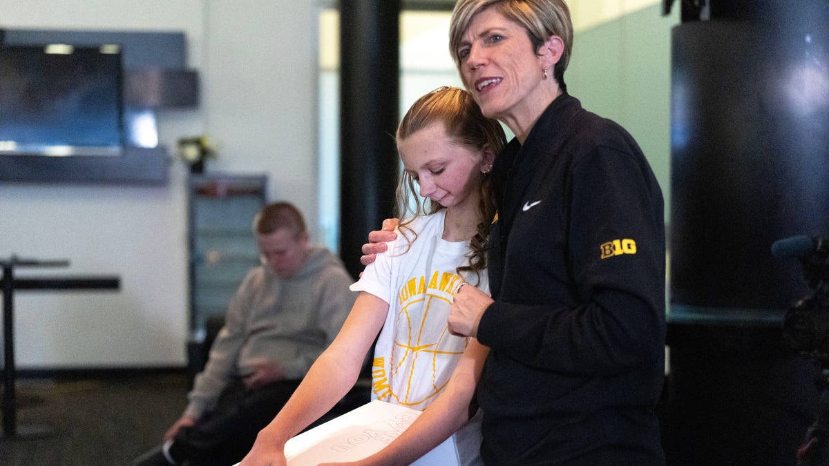 Harper Stribe presenting white, gold and black custom Nike shoes to Iowa women's basketball team