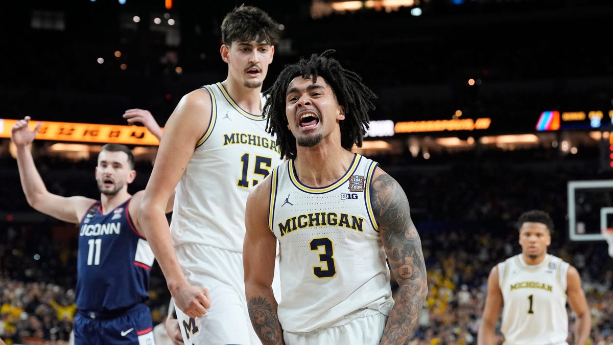 Michigan Wolverines basketball players celebrating their national championship victory with confetti falling at Lucas Oil Stadium