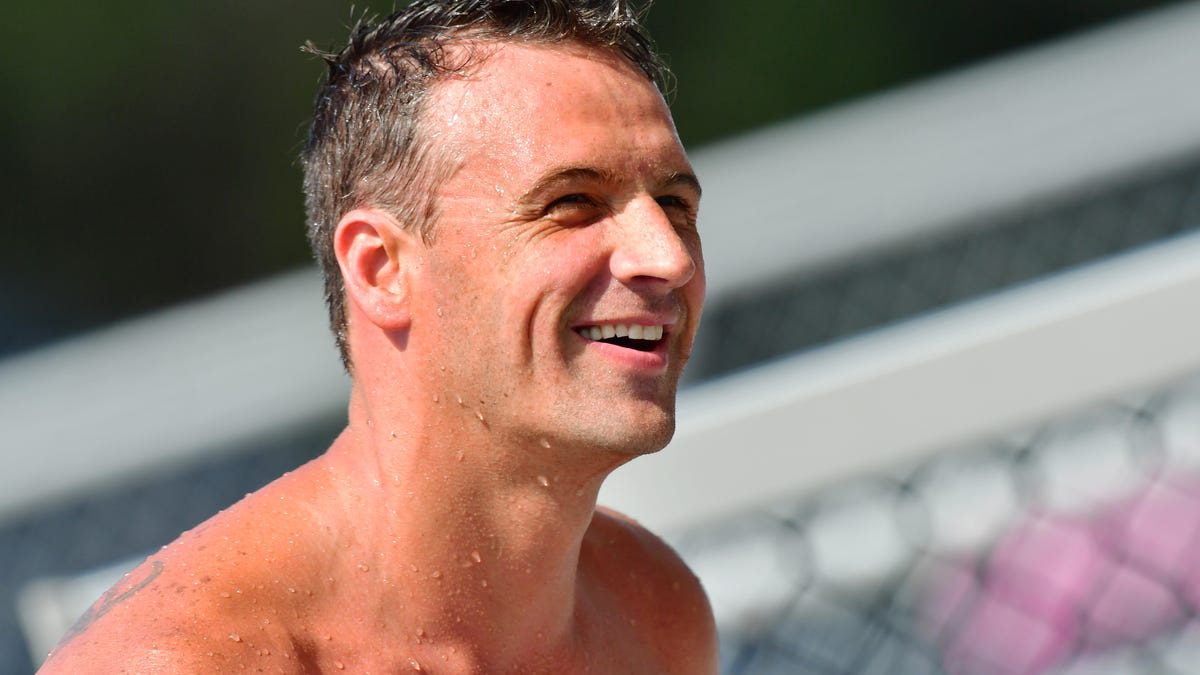 Ryan Lochte smiling at Missouri State swimming facility holding Olympic medals