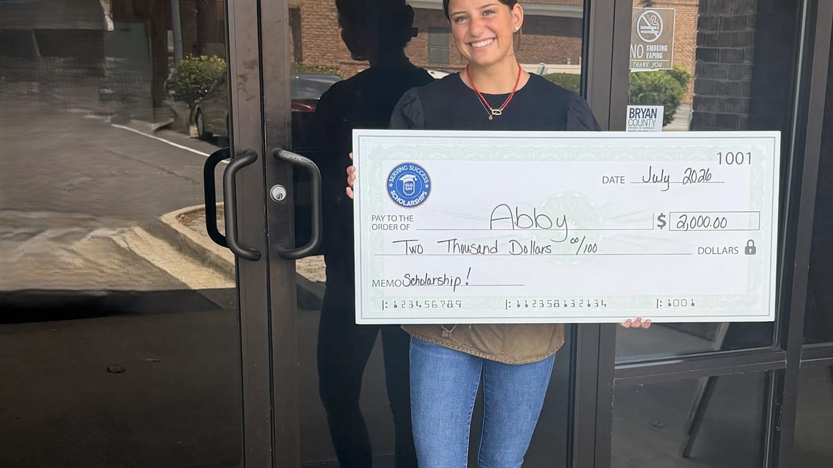 Young female restaurant server smiling while holding scholarship award at 5 Spot restaurant