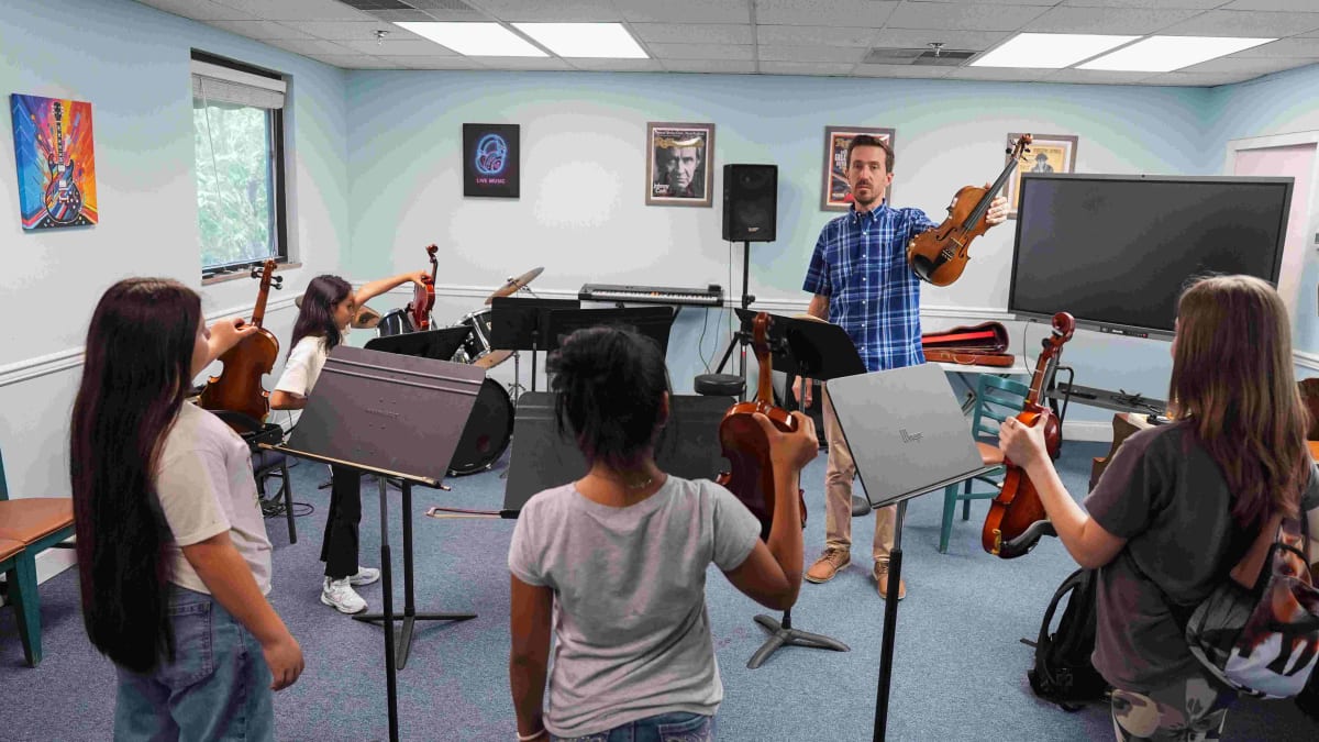 ** Young student learning to play musical instrument with mentor at Knoxville music school
