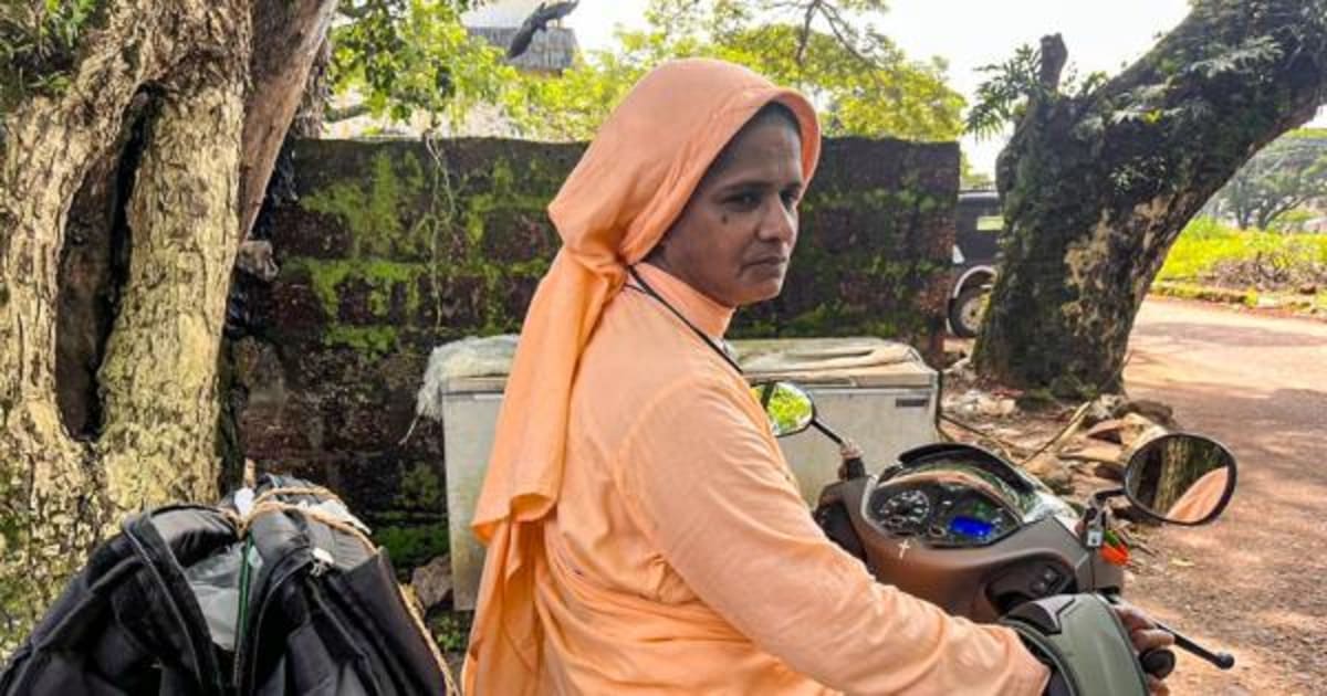 Catholic nun in white habit smiling while delivering food supplies to people on street in Kerala India