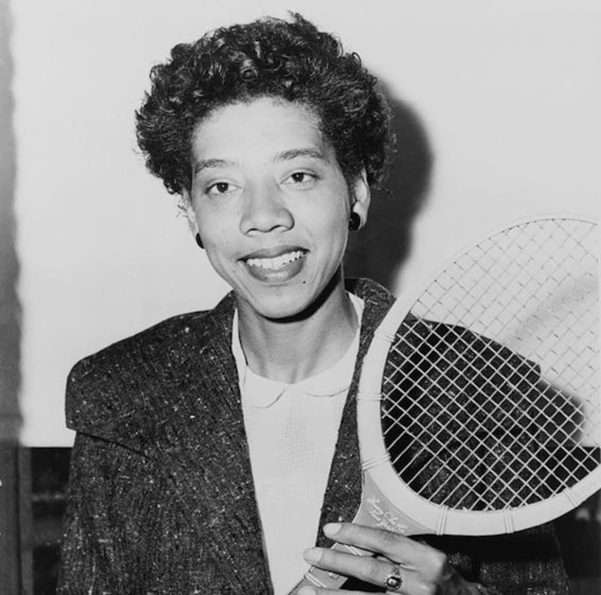 Althea Gibson holding tennis racket on court in the 1950s making tennis history