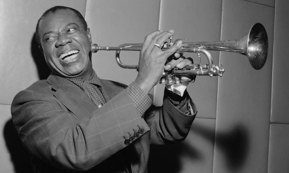 ** Louis Armstrong smiling while holding his trumpet in performance, circa 1960s