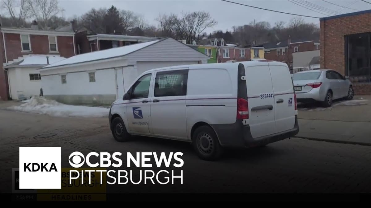 Young postal worker Bruce Armah standing beside mail truck in winter weather holding delivered wallet