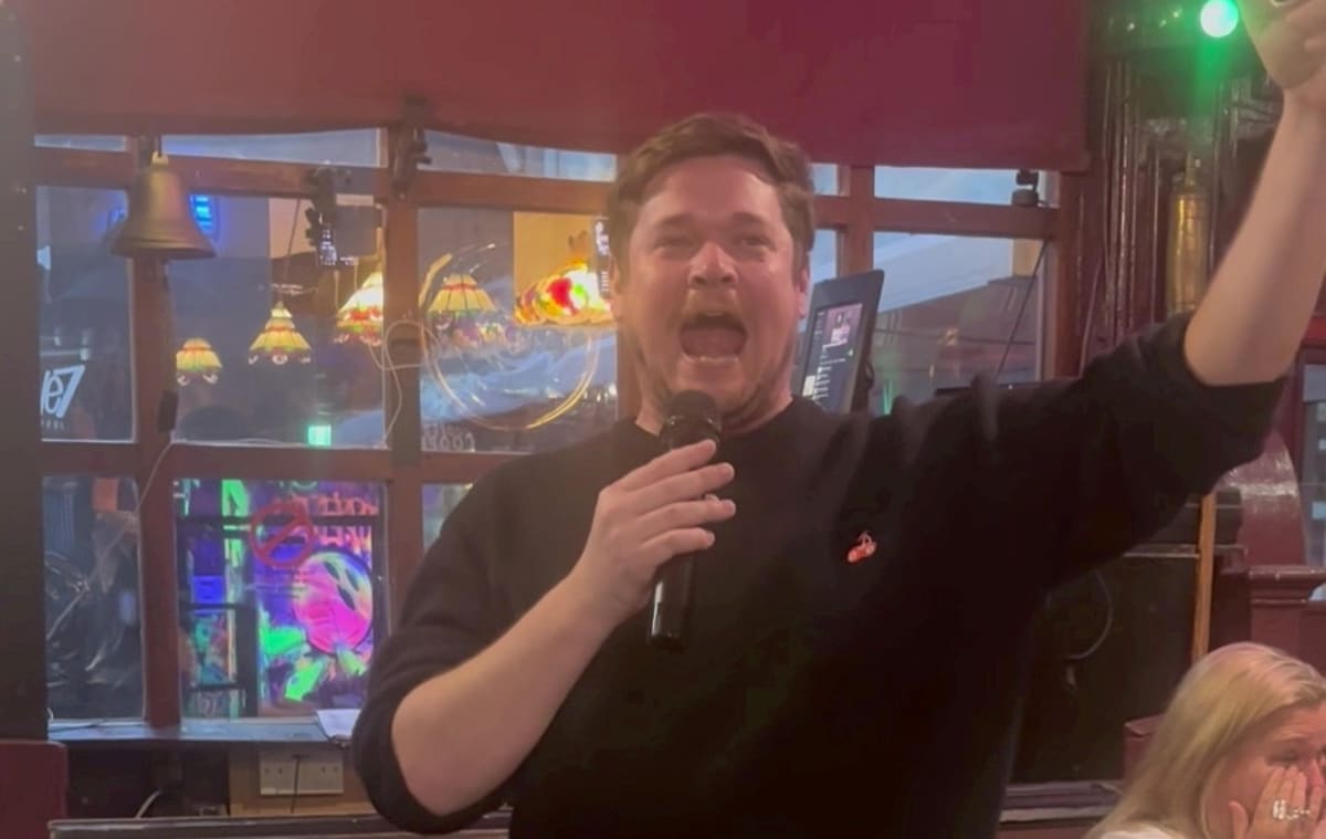 Benjamin Gillham performing opera at Liverpool pub while seated audience watches