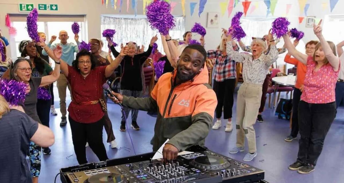 Seniors dancing and singing at energetic daytime DJ party at London community center