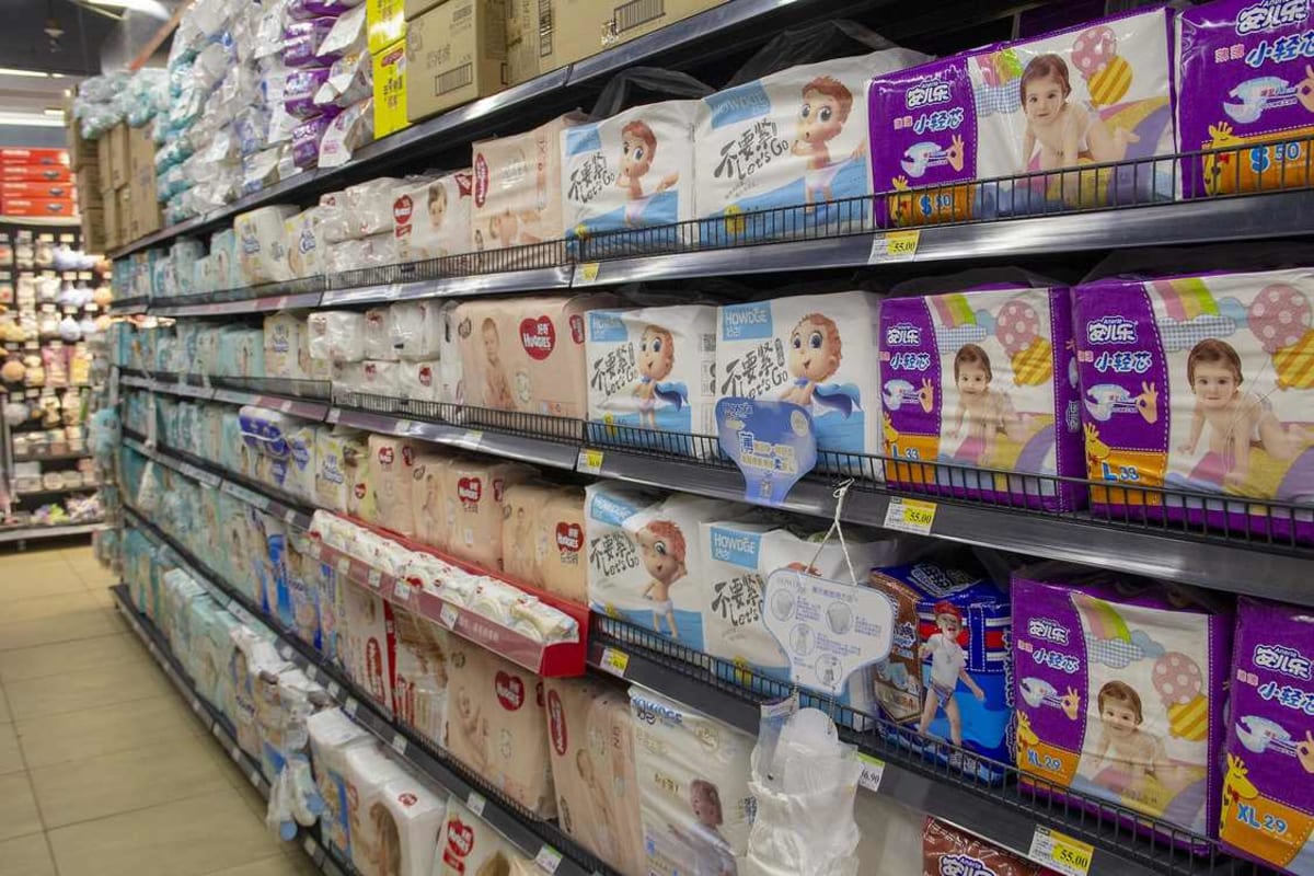 Shelves stocked with various Japanese diaper brands in colorful packaging at retail store