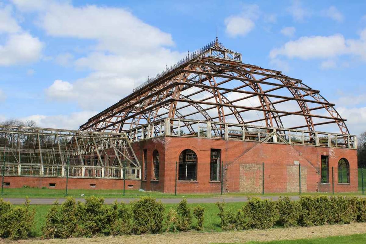 Victorian iron and glass greenhouse with ornate framework standing in Glasgow park