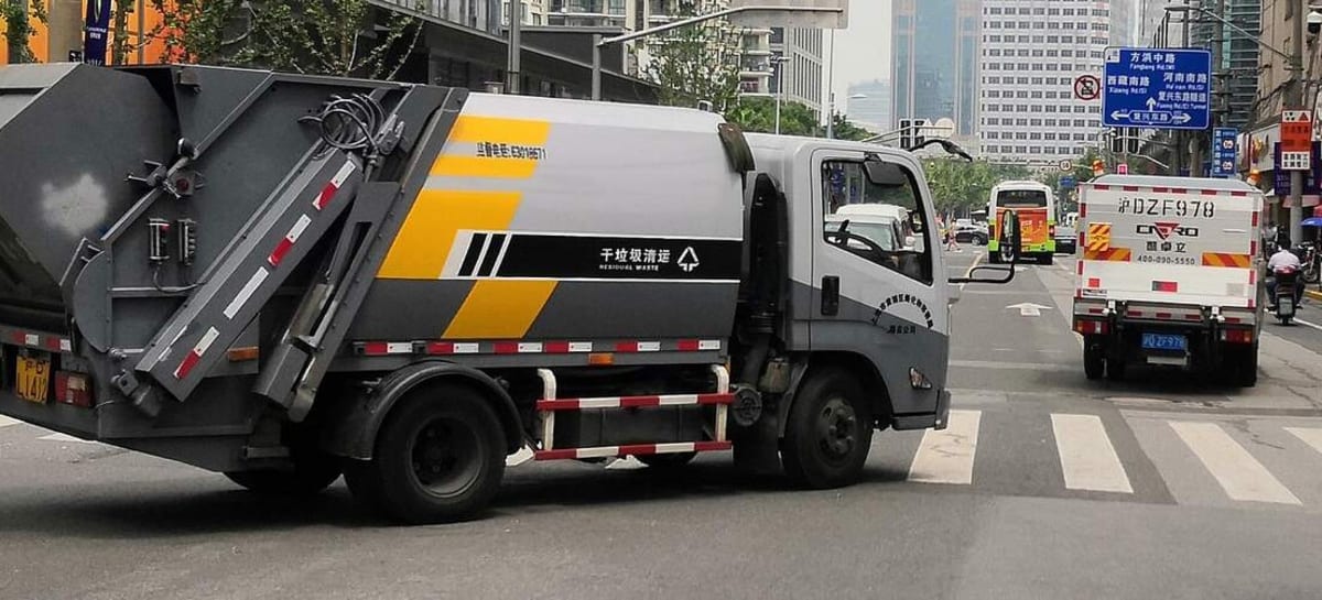 Waste collection trucks driving through modern Shanghai streets with recycling bins visible