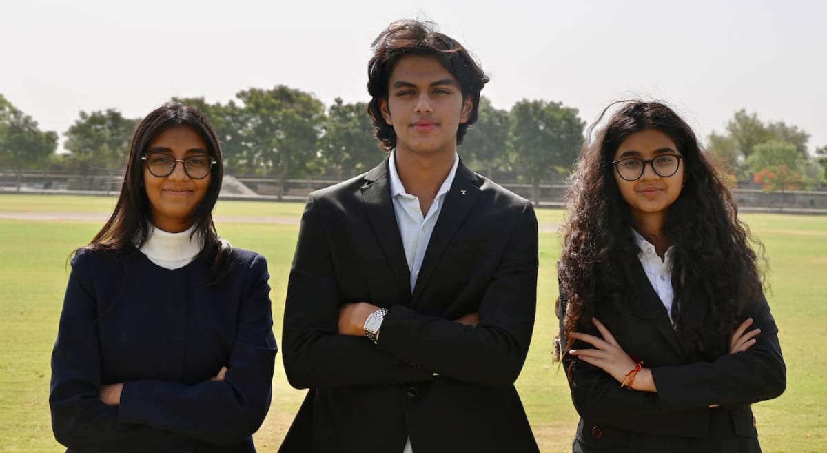 Three Indian teenagers smiling together holding their Plas-Stick tamarind powder microplastic removal invention