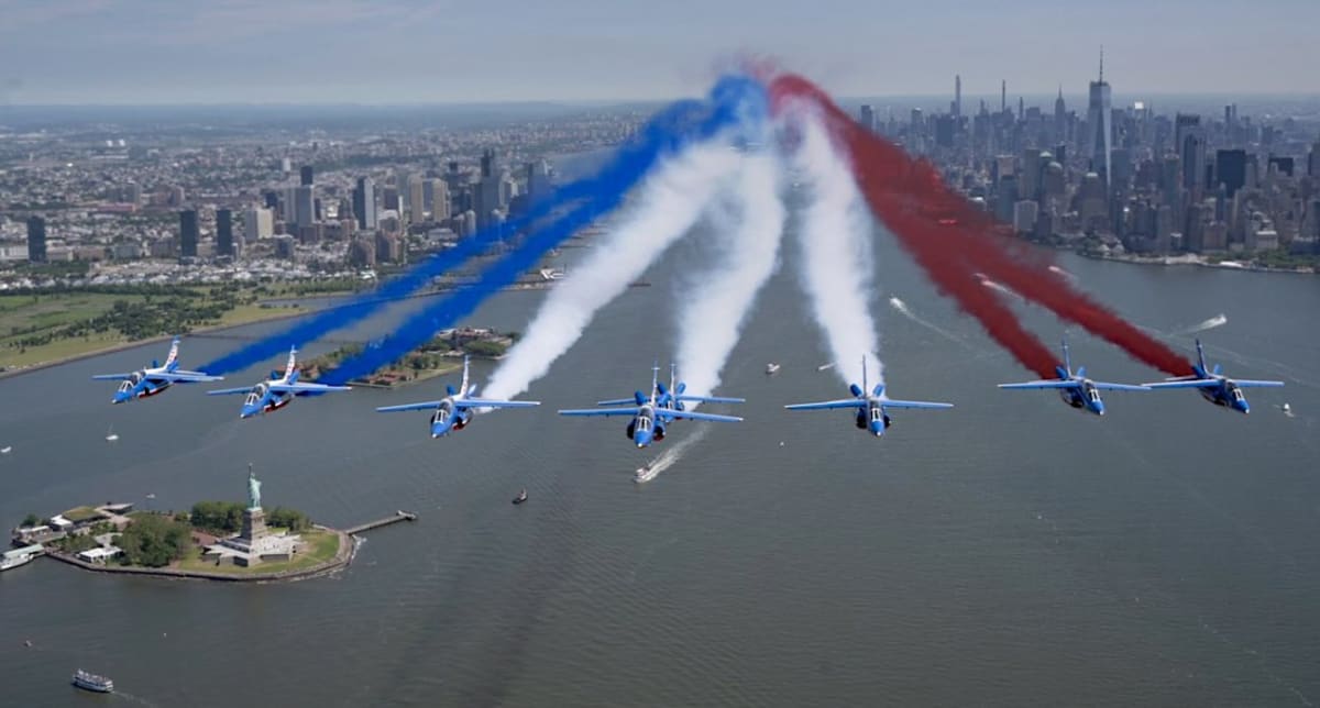 French Patrouille de France jets trailing red white and blue smoke over Statue of Liberty