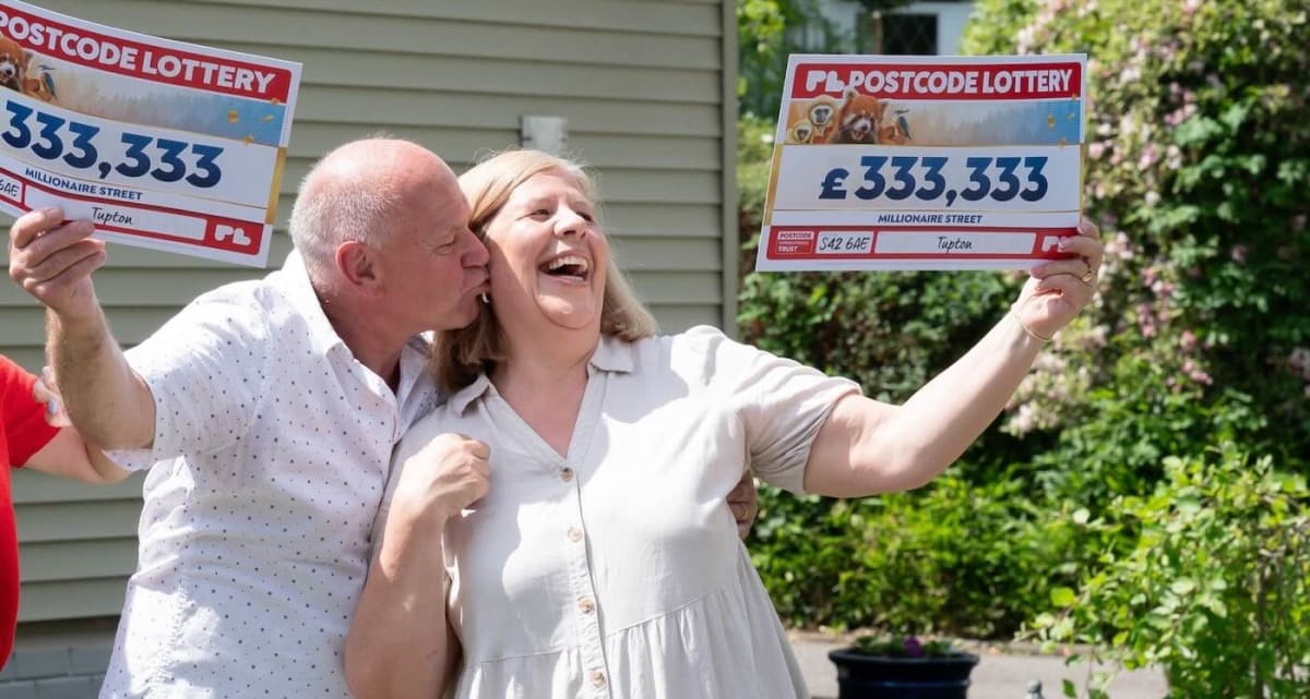 Smiling retired couple Allan and Bev Taylor holding two large lottery prize checks