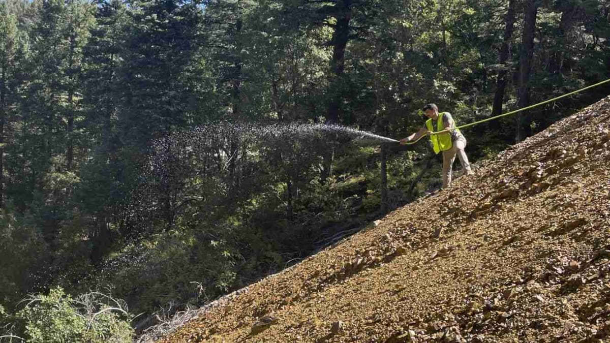 Researcher applying enzyme solution to stabilize contaminated waste at abandoned Arizona mine site