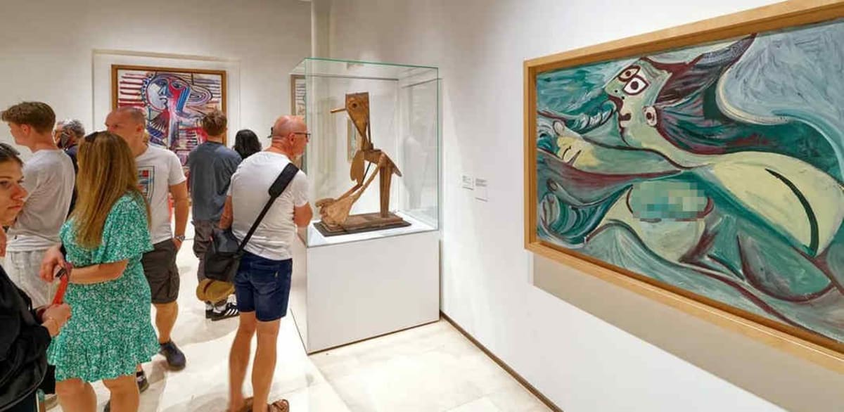 Exterior of Museo Picasso gallery in Malaga with visitors entering through glass doors
