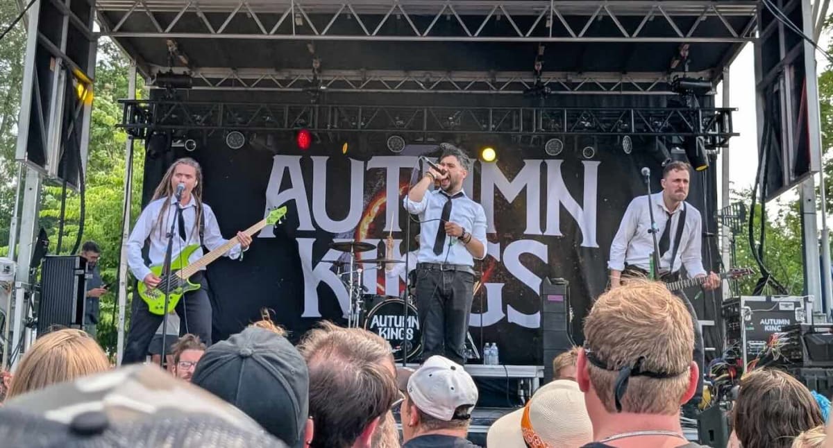 Ernie standing with three members of metal band The Autumn Kings beside red Ford Explorer