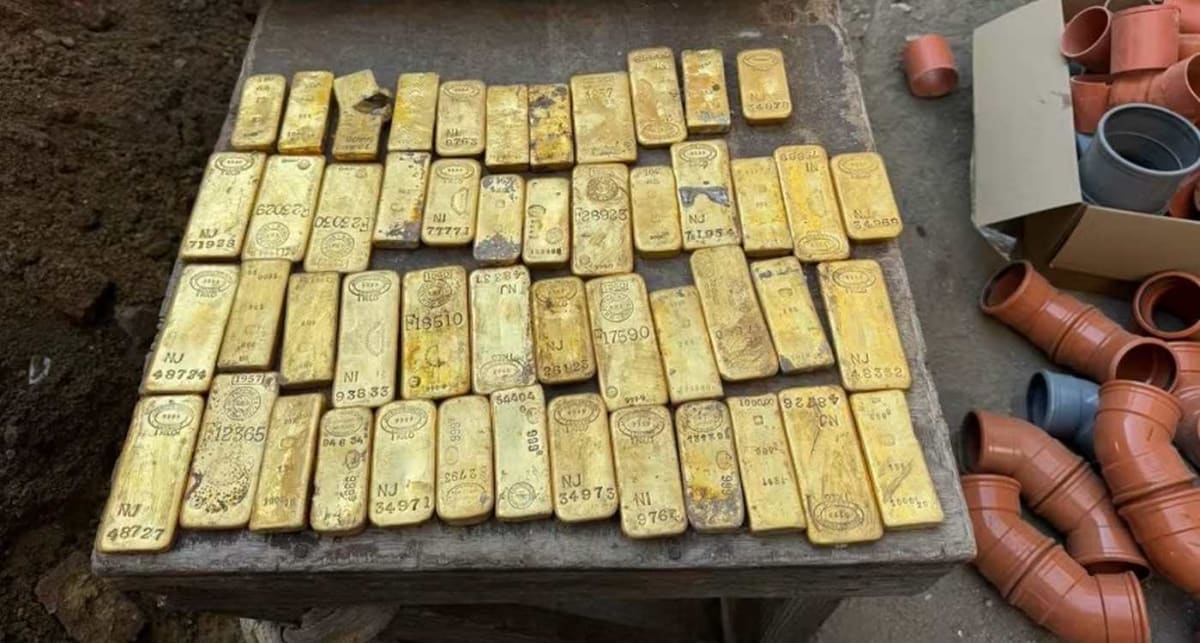 Rows of recovered gold bars displayed on table with visible jackhammer mark on one bar