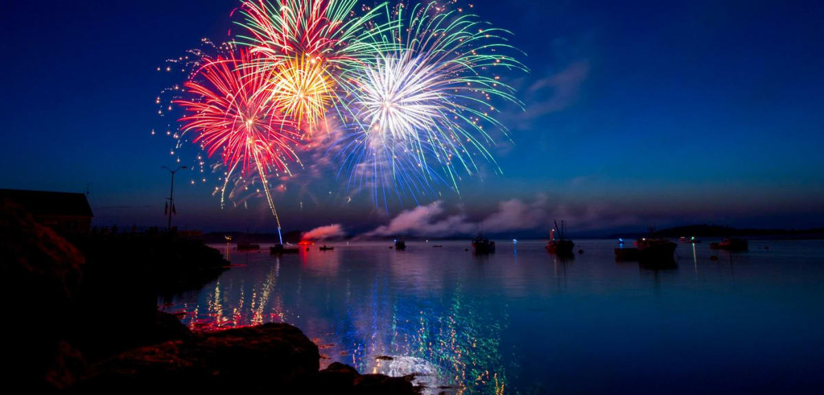 Colorful fireworks exploding over water with biodegradable shells dissolving below